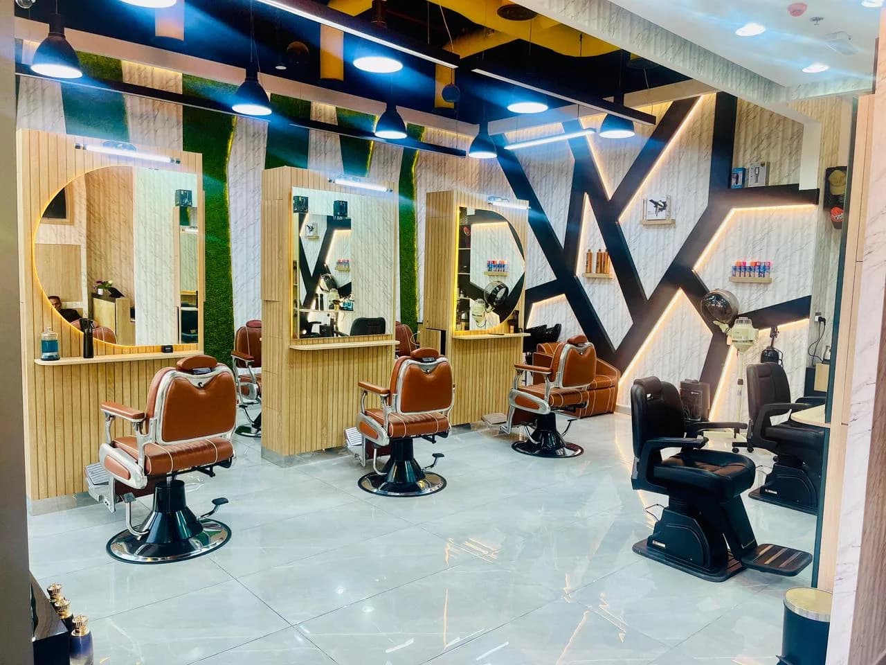 Top One barber station with three vintage tan leather chairs, round mirrors, and moss-panel wall