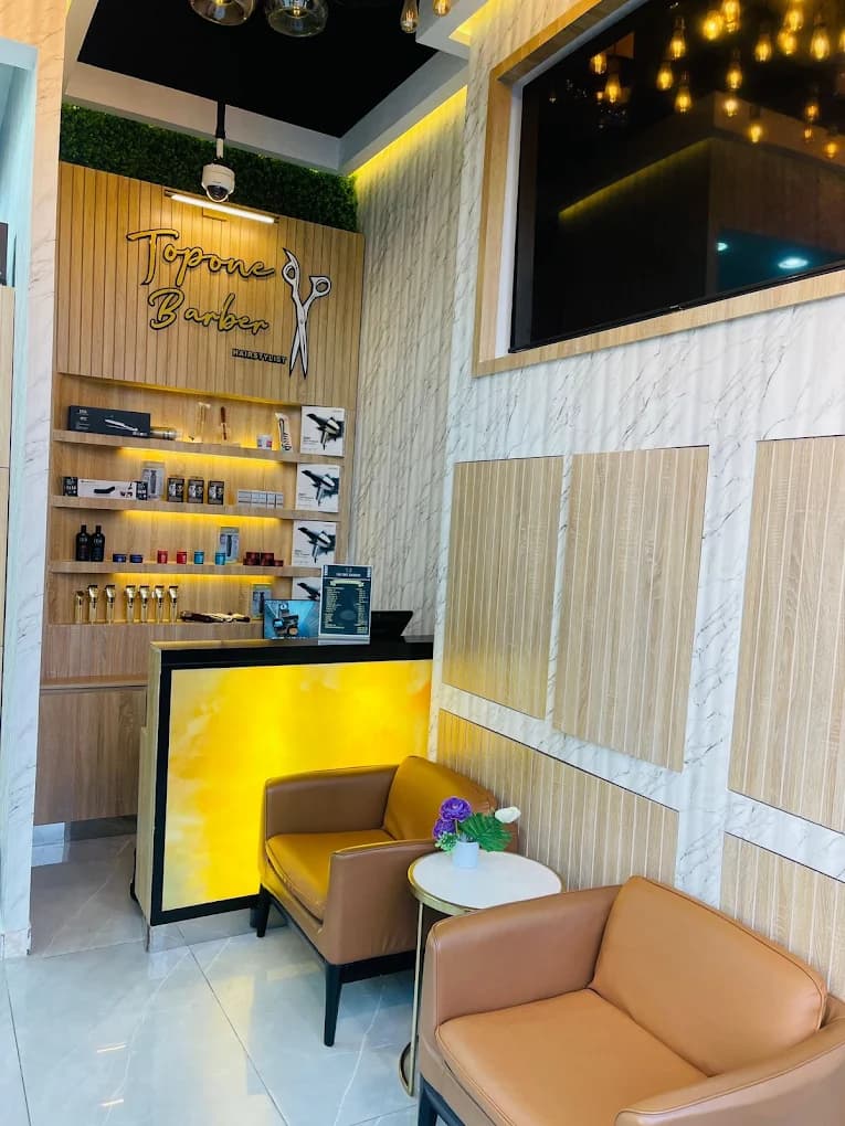 Topone Barber wall sign and shelving beside the lounge seating area with a wall-mounted TV