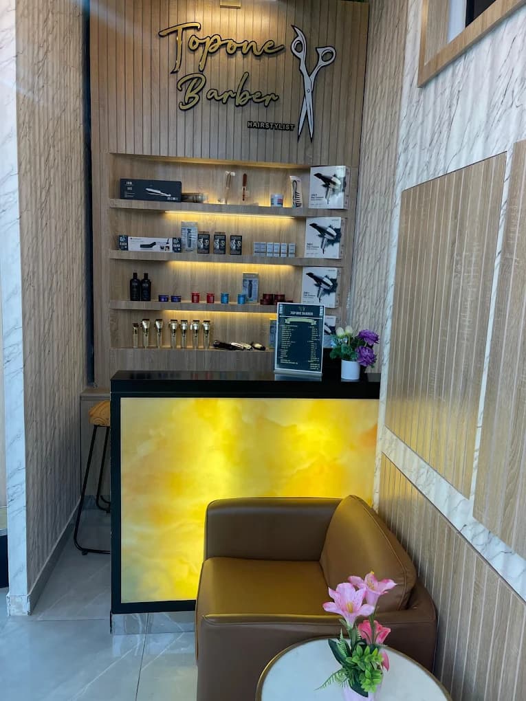 Topone Barber reception counter with branded wall sign, product shelving, and waiting couch