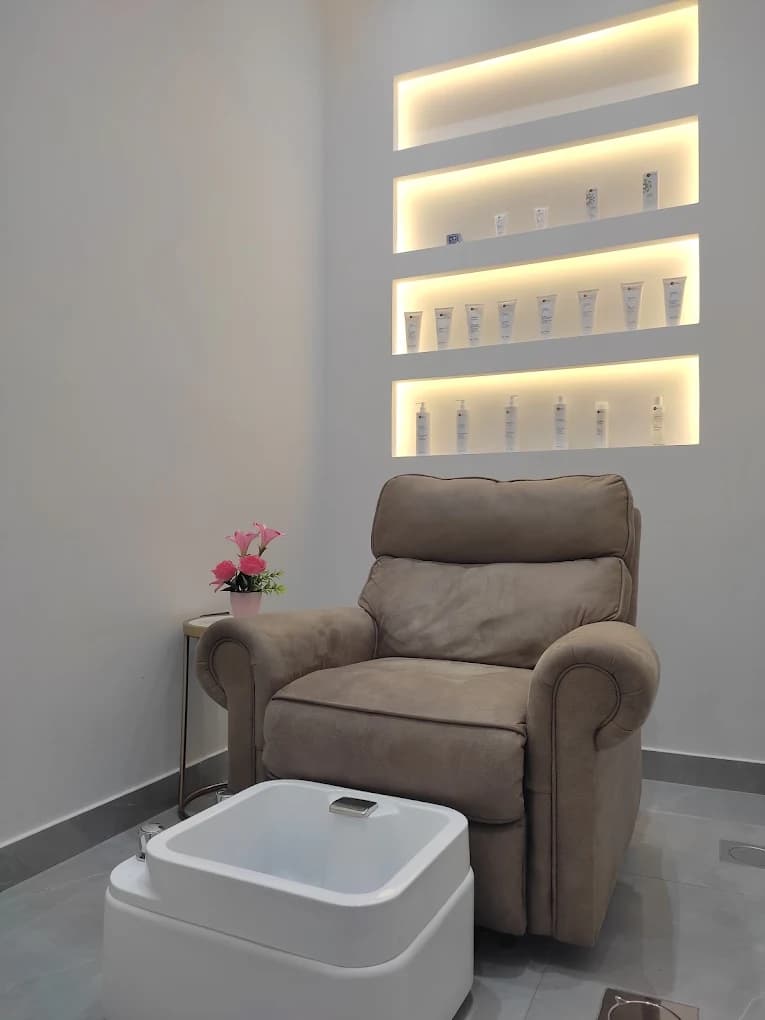 Spa recliner chair beneath backlit shelving of skincare products